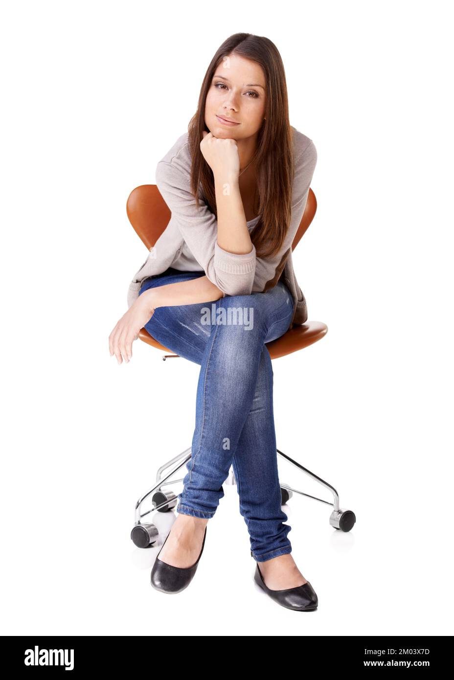Shes got a thoughtful side. Studio shot of a beautiful young woman sitting on a chair against a white background. Stock Photo