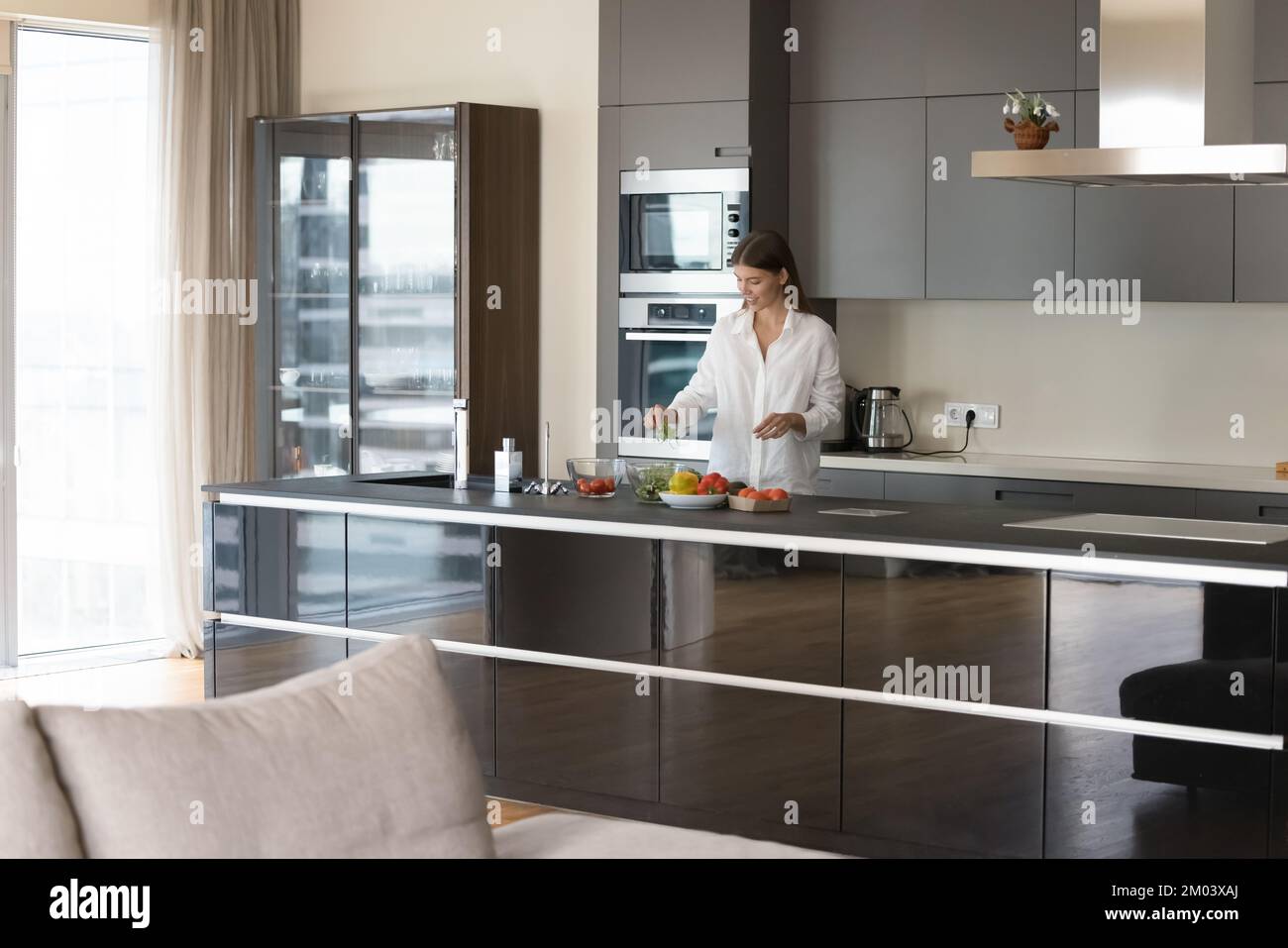 Young chef woman cooking salad in contemporary home kitchen interior Stock Photo