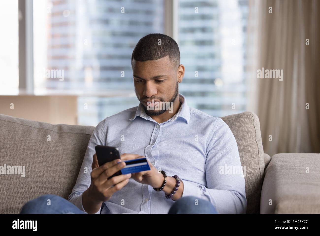 Focused mobile phone user man using credit card Stock Photo