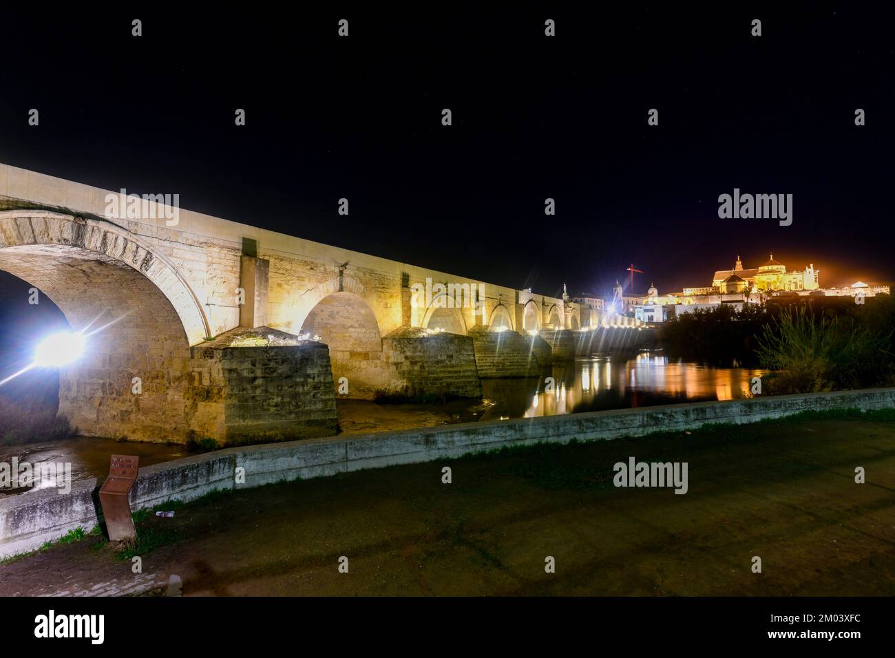 View of the Roman Bridge, a stone bridge that spans the river Guadalquivir in Cordoba, Spain at night. Stock Photo