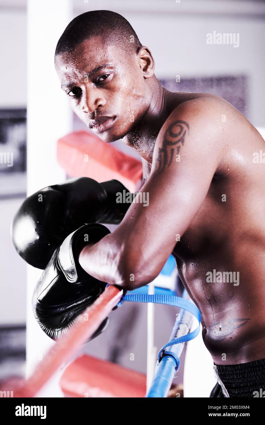 Theres steel in his eyes and strength in his punch. An african american boxer leaning on the ropes and looking at you with resolve. Stock Photo