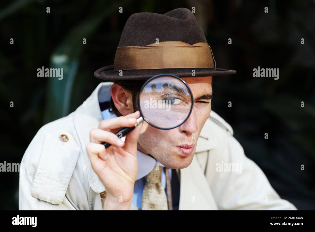 Finding all the clues. Curious private investigator looking through a magnifying glass. Stock Photo