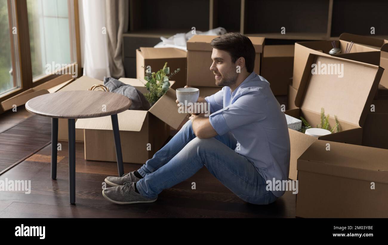 Happy thoughtful home owner man taking break from relocation activity Stock Photo