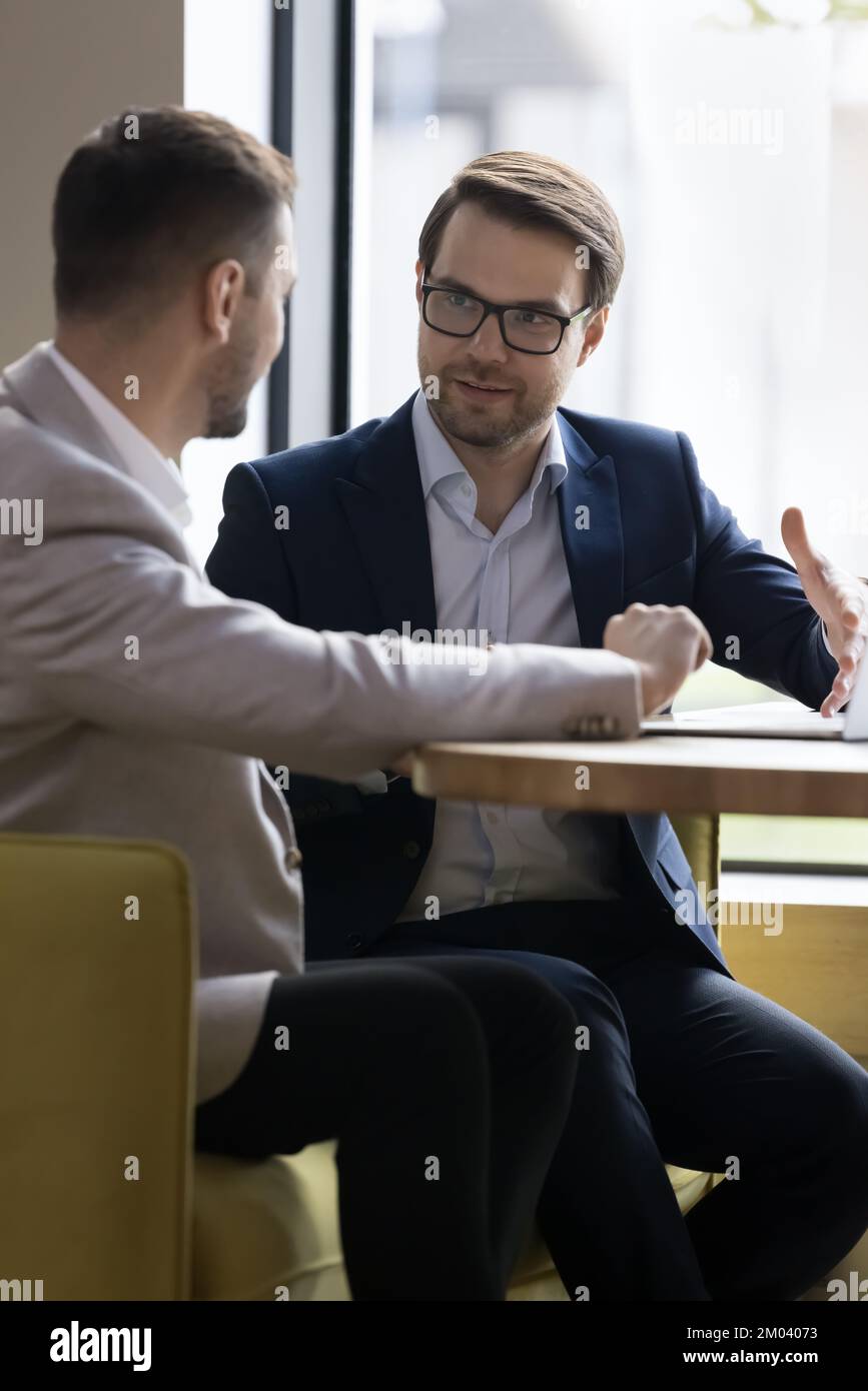 Two businessmen discuss business meet in company office, vertical image