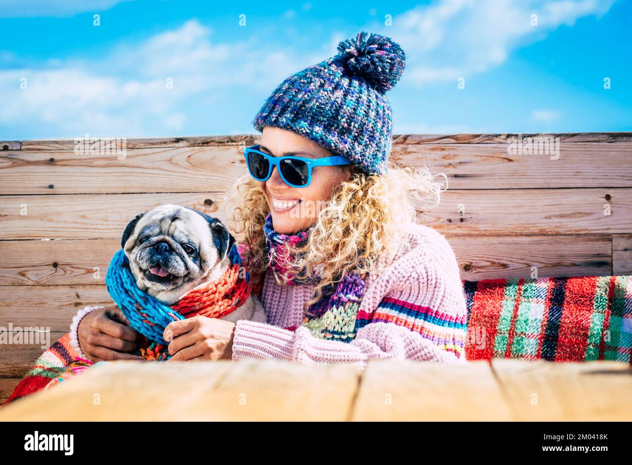Portrait of joy woman hugging her old dog in outdoor leisure activity in winter day holiday. One female people in friendship with dog pug. People and Stock Photo