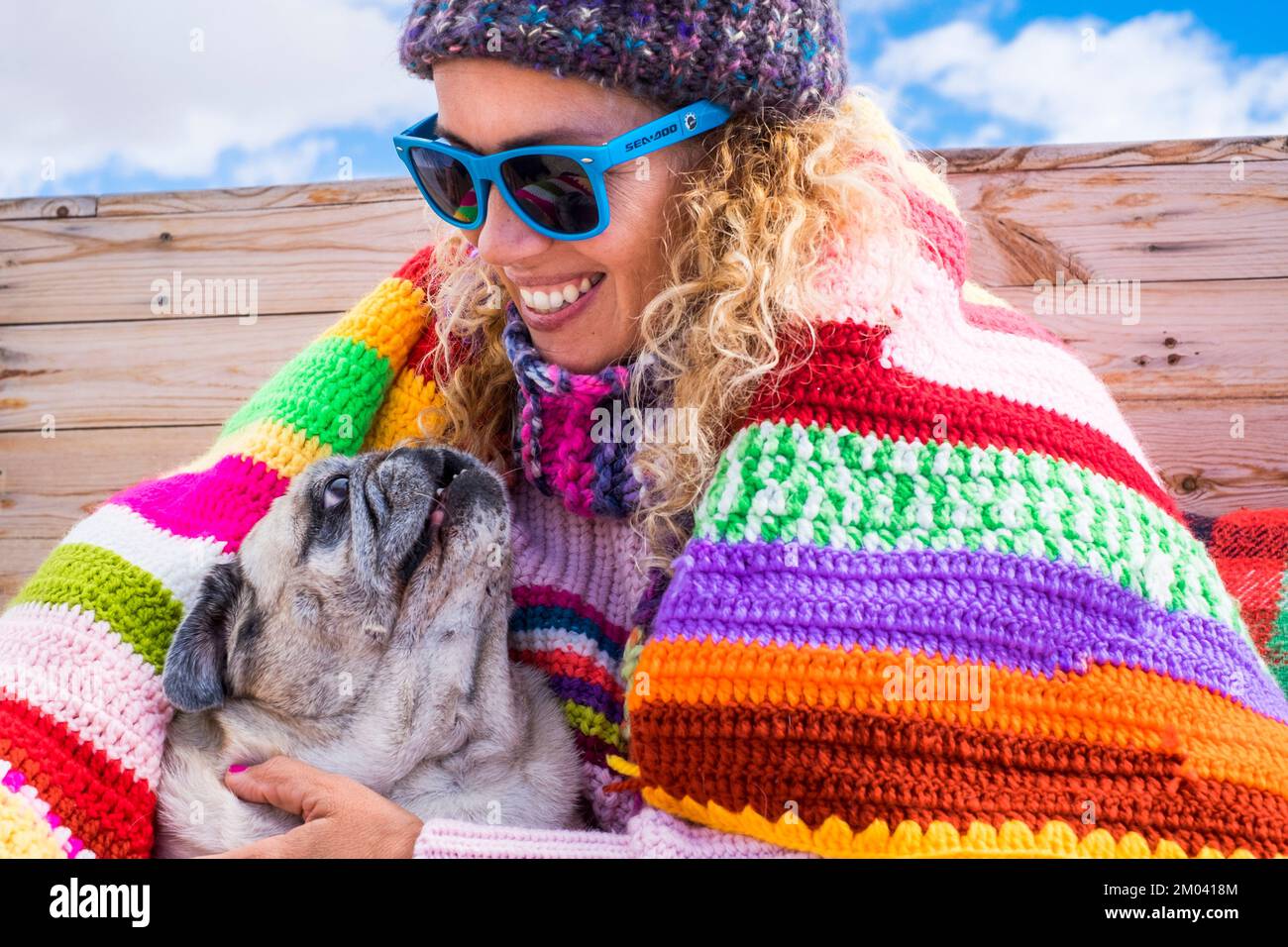 One happy woman smiling with her best friend companion dog pug sitting near her. Winter outdoor leisure activity with people in friendship with animal Stock Photo