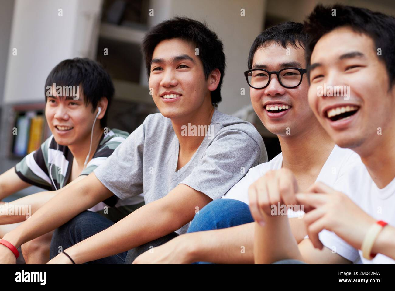 Chilling with the guys. a group of asian friends sitting outdoors. Stock Photo