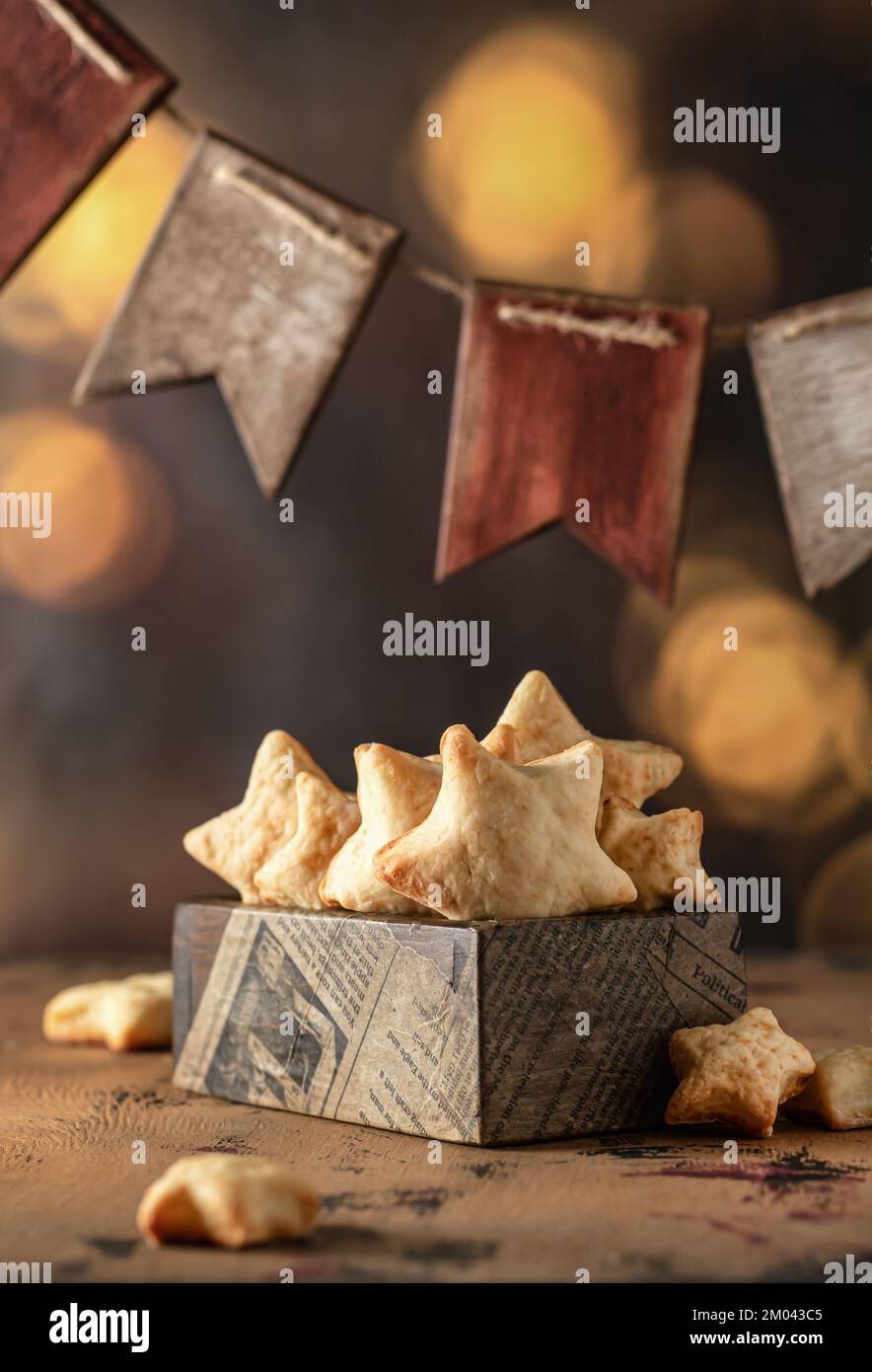 Homemade Christmas shortbread star shape sugar cookies with sugar powder in wooden box, with garland of wooden flags and bokeh lights in the Stock Photo