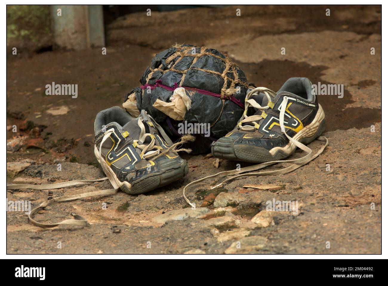 A child’s pair of second hand shoes and his home made football ball made from old plastic shopping bags and bits of string to hold it together. Stock Photo