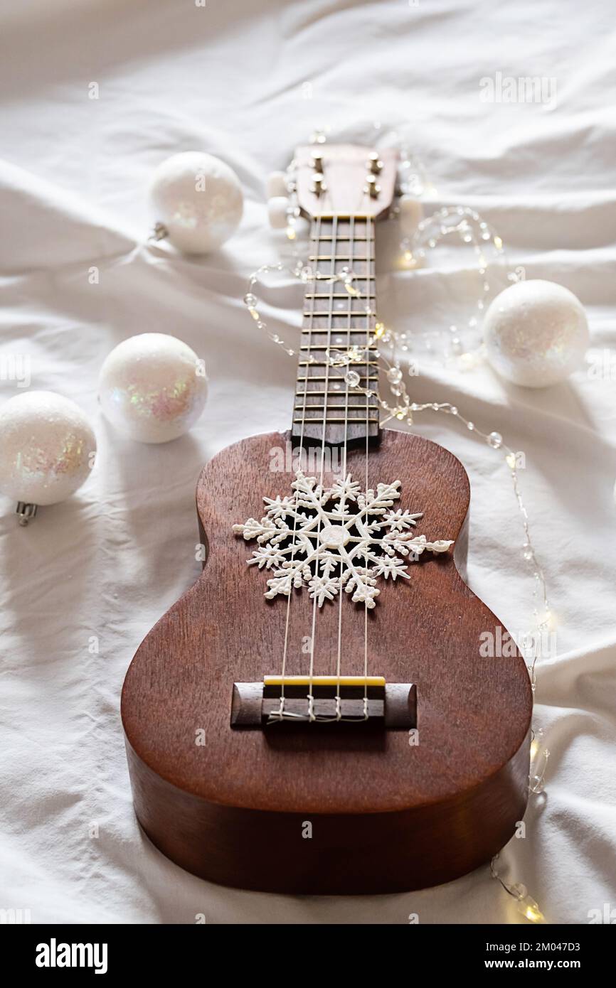 Ukulele guitar, Christmas balls and garland lights on white. Winter festive  composition Stock Photo - Alamy