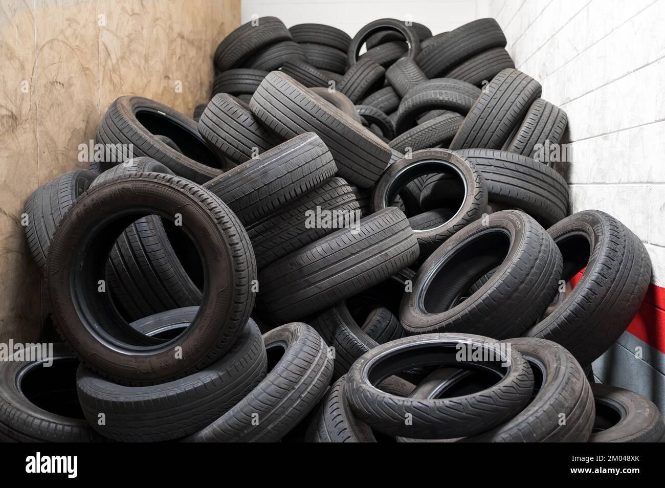 Heap of old black vehicle tires stacked in small room of disposal