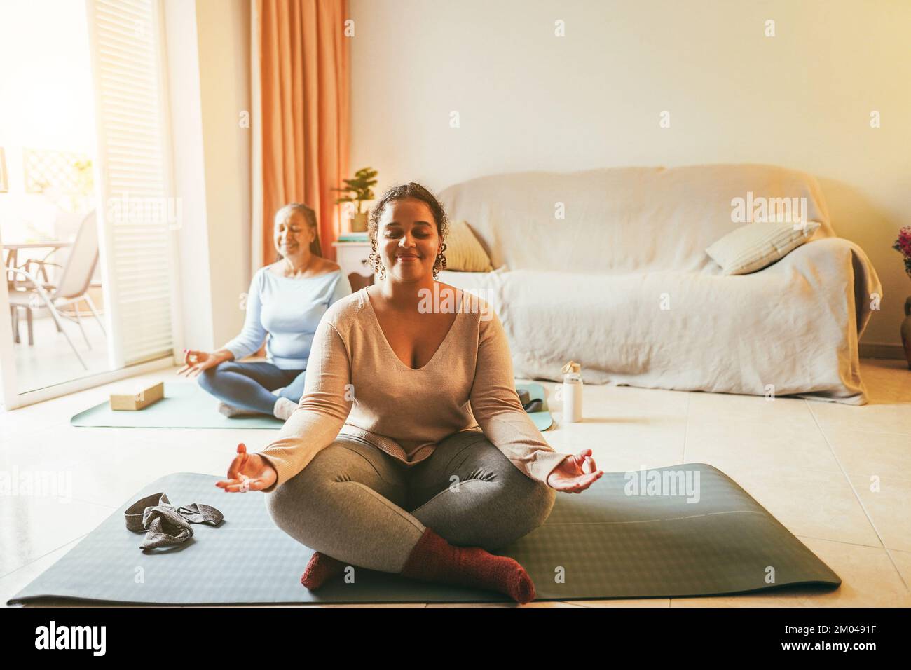 Mother and daughter doing yoga exercises at home together during winter ...