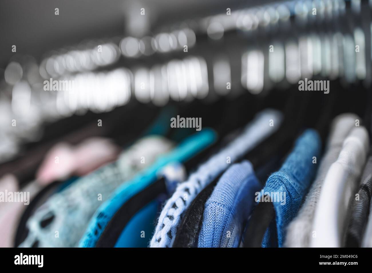 organizing and tidying up conceptual still-life, wardrobe with colour coded selection of different knits and blouses lined up on black flocked hangers Stock Photo