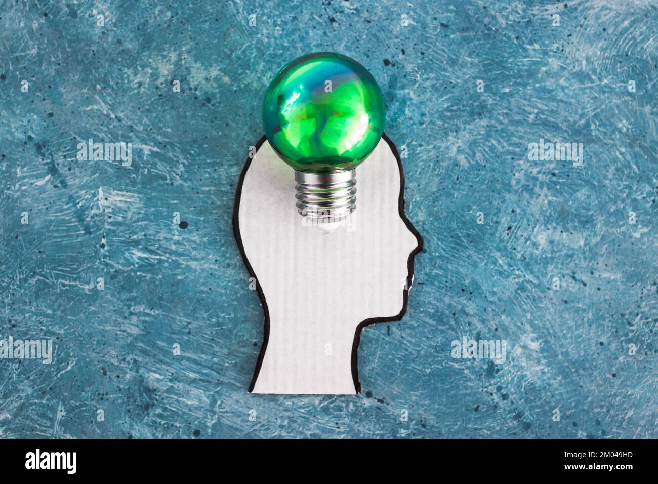 cardboard head silhouette with green light bulb metaphor of ideas for the green economy on blue background Stock Photo
