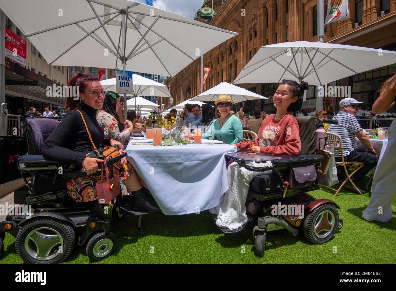 Two women in motorised wheelchairs smile and enjoy the day at Sydney’s 2022 Open For Lunch in Australia event held in George Street Stock Photo