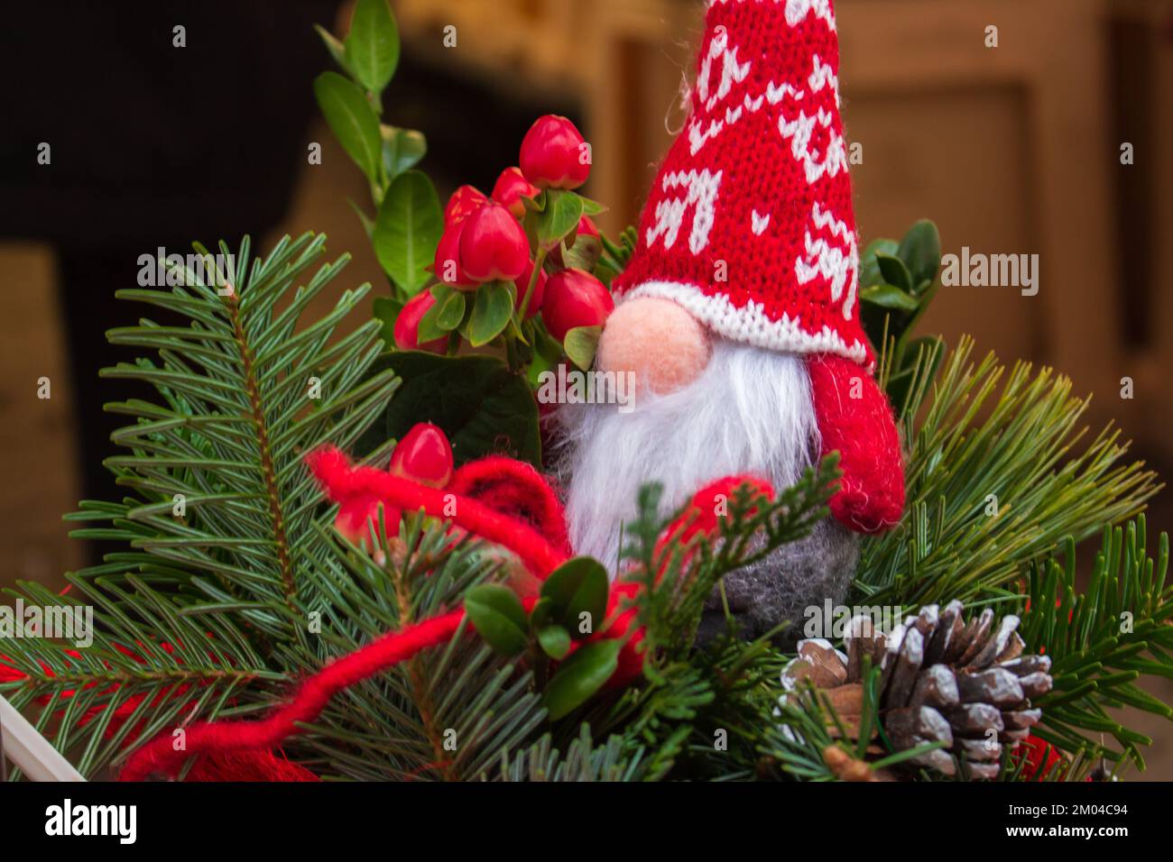 Cute gnome toy on Christmas tree. Small dwarf doll in red hat. Santa Claus doll on Christmas market. Christmas market. Christmas decor on pine tree. Stock Photo