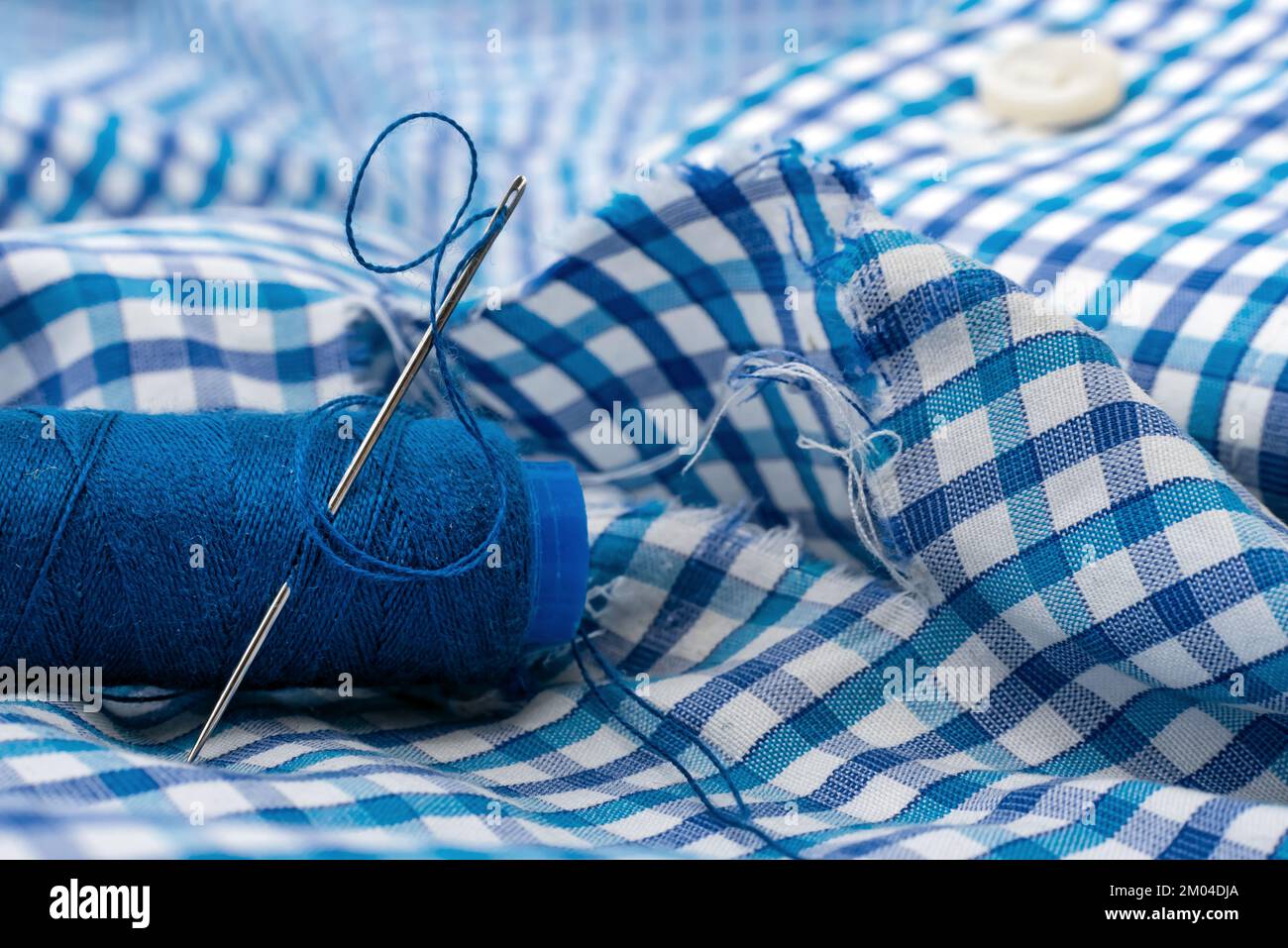 Needle and thread on a checkered fabric closeup. Seamstress or tailor