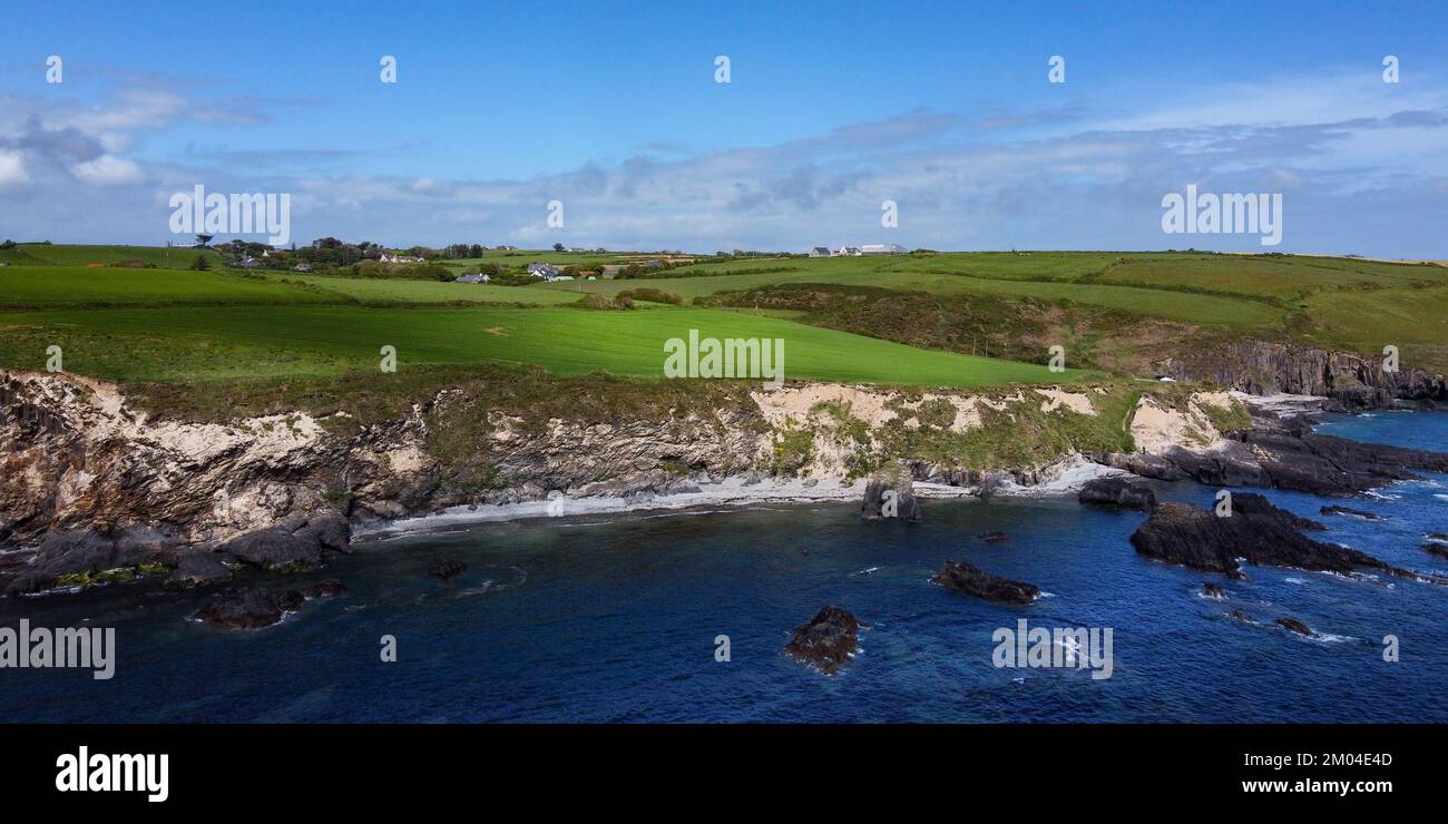 Green hills on the Atlantic Ocean on a sunny spring day. Blue sky over the sea coast. The coastline of Ireland, West Cork. Aerial photo. Stock Photo
