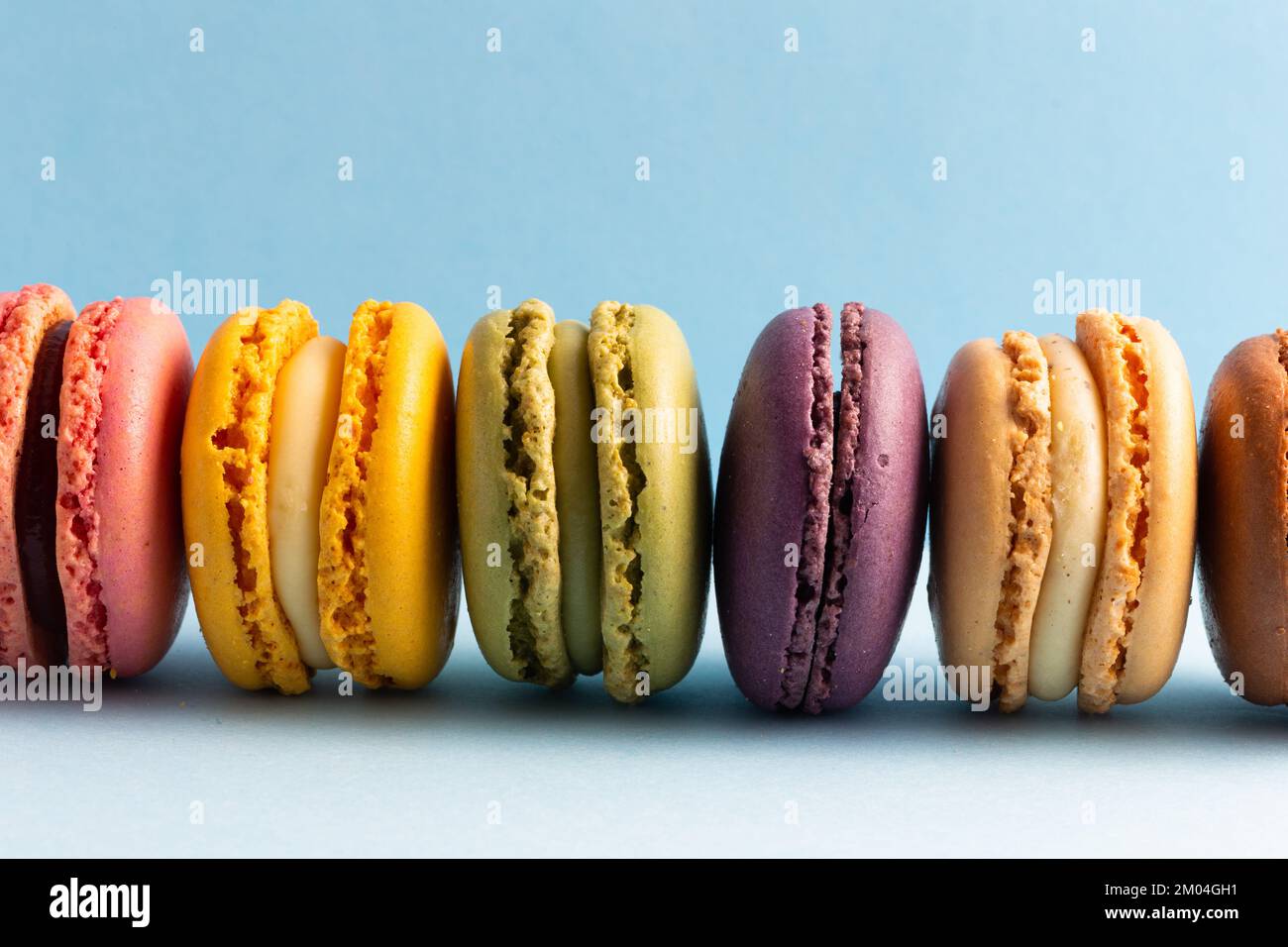 colored macaroons in a row on a blue background Stock Photo