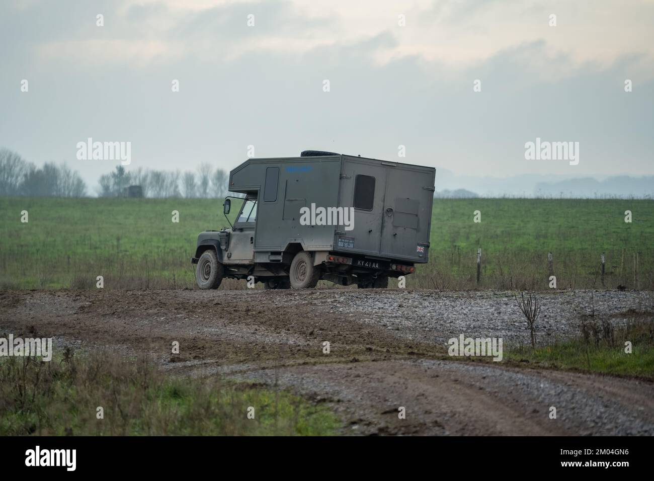 British army Land Rover Defender Wolf medical assistance light utility vehicle moving along a mud track on a military exercise, Wiltshire UK Stock Photo