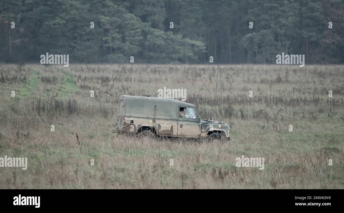 British army Land Rover Defender Wolf light utility vehicle moving along a mud track on a military exercise, Wiltshire UK Stock Photo