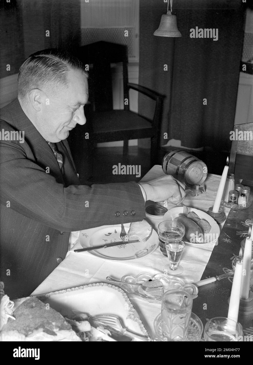 At christmas in the 1940s. A man is having christmas dinner and enjoys the typical traditional food and drinks from the table. Sweden december 1940 Kristoffersson 42-9 Stock Photo