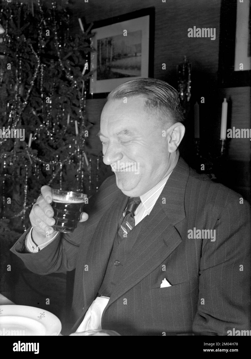 At christmas in the 1940s. A man is having christmas dinner and to this he also looks as if he enjoys the typical traditional christmas drink. Sweden december 1940 Kristoffersson 42-8 Stock Photo