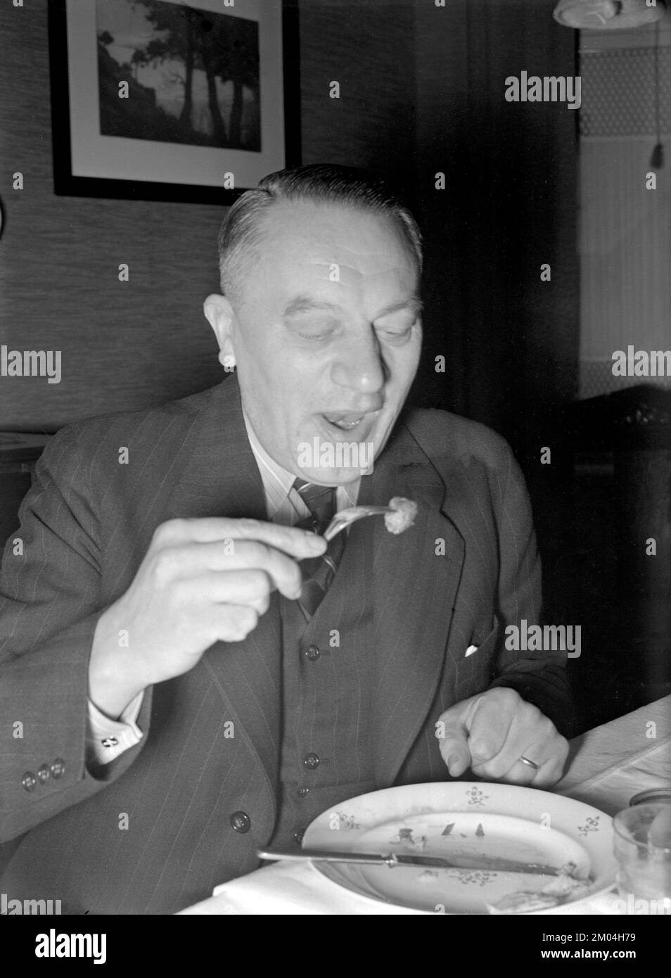 At christmas in the 1940s. A man is having christmas dinner and has a meatball on his fork ready to eat.  Sweden december 1940 Kristoffersson 42-10 Stock Photo