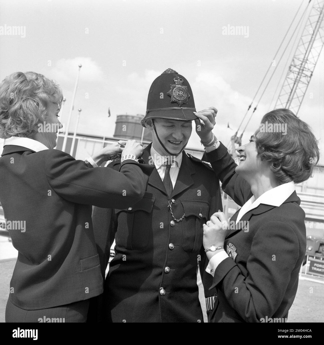 Being a bobby in the 1960s. The British exhibition in Stockholm 18 may - 3 june 1962. A man in a British policemans uniform is having the details seen to by two women. Sweden 1962 Stock Photo