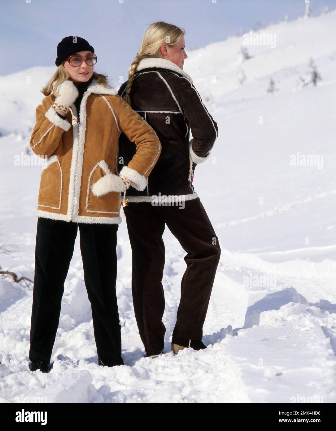 Fashion in the 1980s. Two young models standing in the snow for a photo shoot. They are wearing warm winter jackets and trousers. Sweden march 1980 Stock Photo