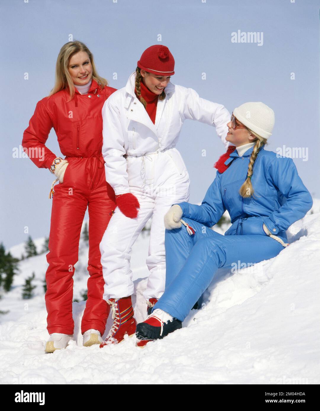 Fashion in the 1980s. Three young models in the snow for a photo shoot. They are wearing warm winter overalls. Sweden march 1980 Stock Photo