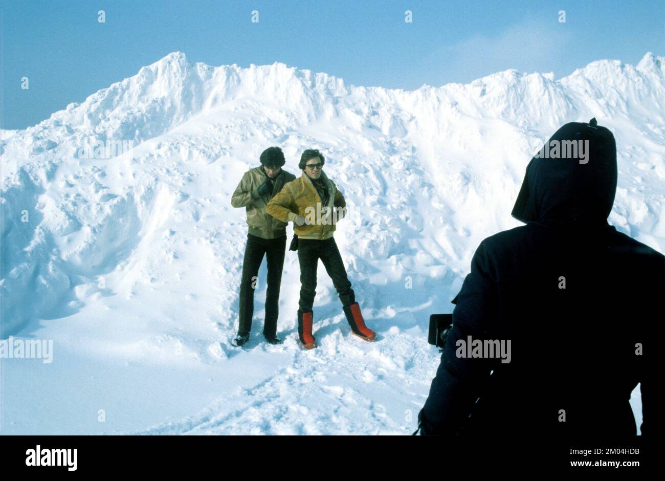 Fashion in the 1980s. Two young male models standing in the snow for a photo shoot. They are wearing warm winter jackets and trousers and one of them the decades typical winter boots. Sweden march 1980 Stock Photo