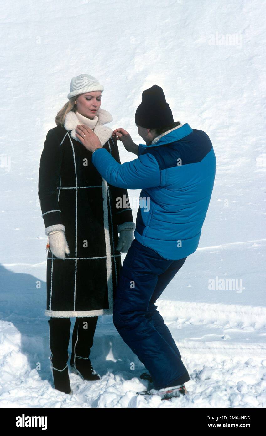 Fashion in the 1980s. A young model is being prepared for a photo shoot. She is wearing the years winter fashion, a warm coat hand cap. An assistant is seen finishing the details. Sweden march 1980 Stock Photo