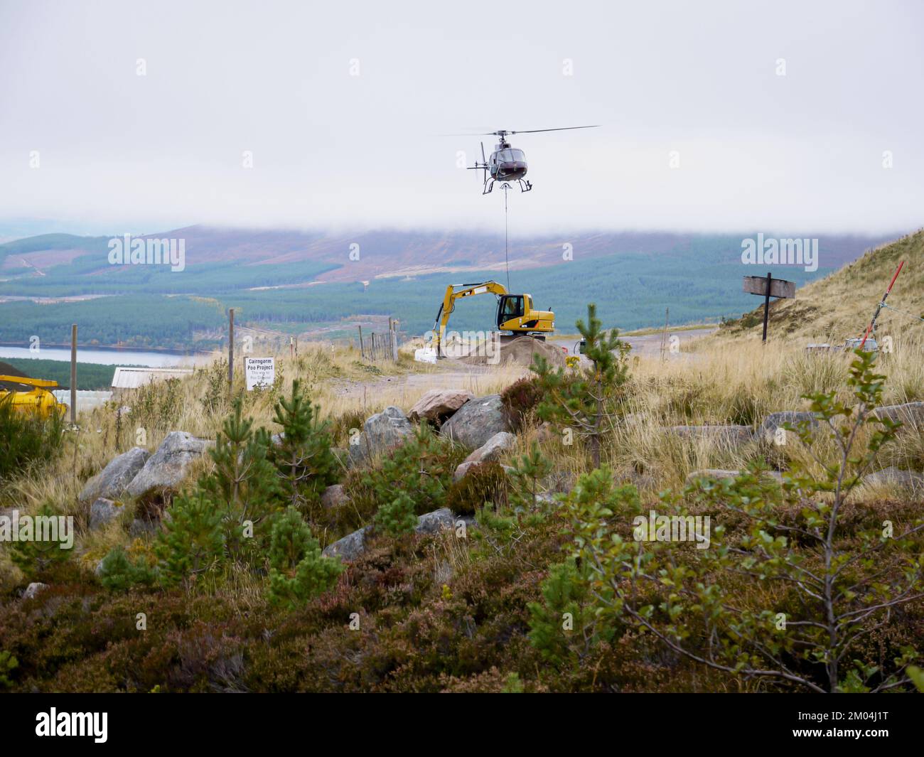 Aviemore, Scotland UK. Taken on 14 October 2009. Helicopter lifts bags of stone in the air. Man attaching rope to tonne bags of stone. Stock Photo