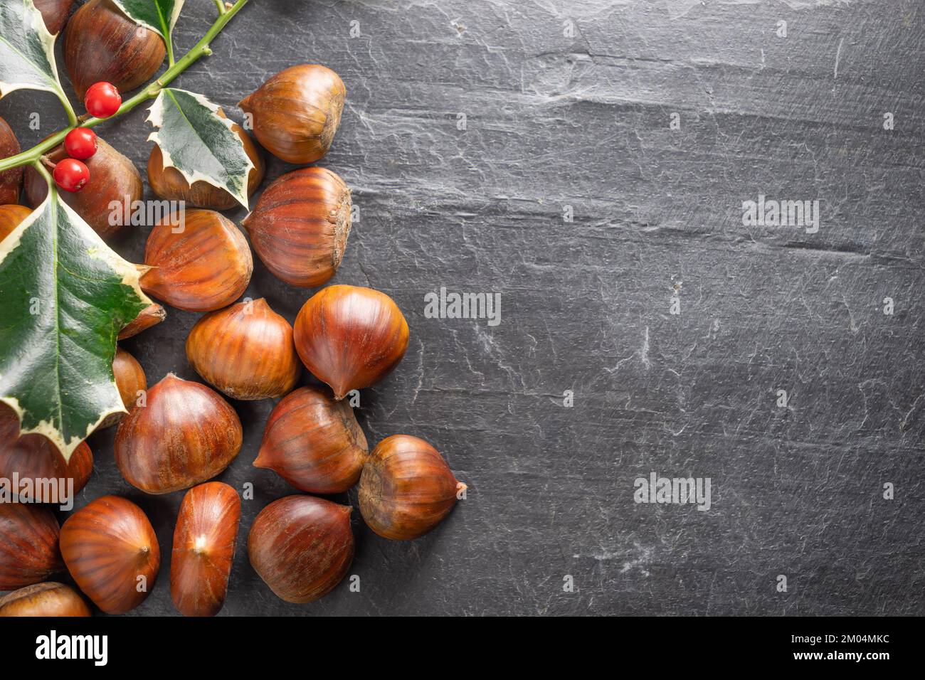 Chestnuts with Christmas holly Stock Photo
