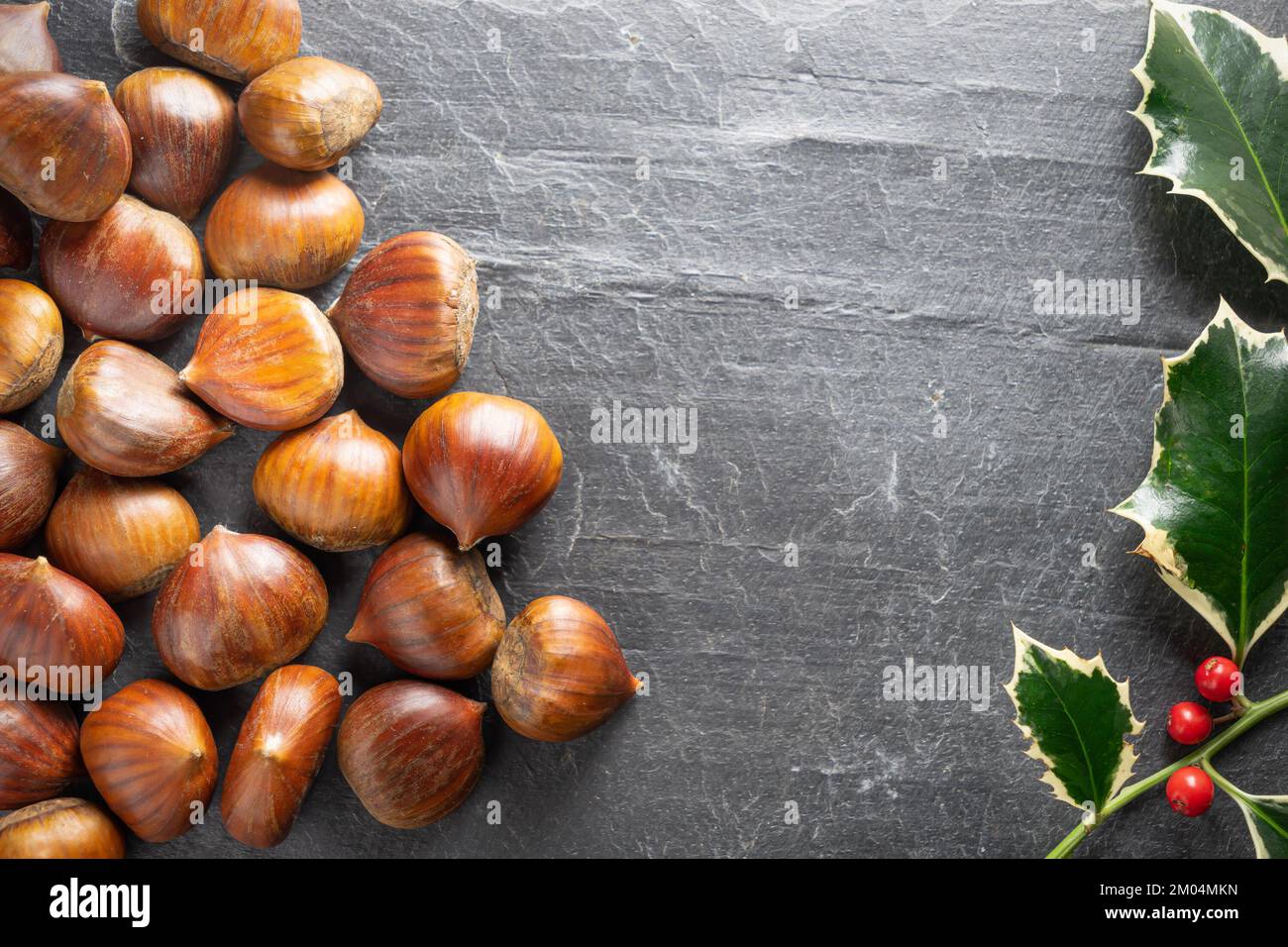 Chestnuts with Christmas holly Stock Photo