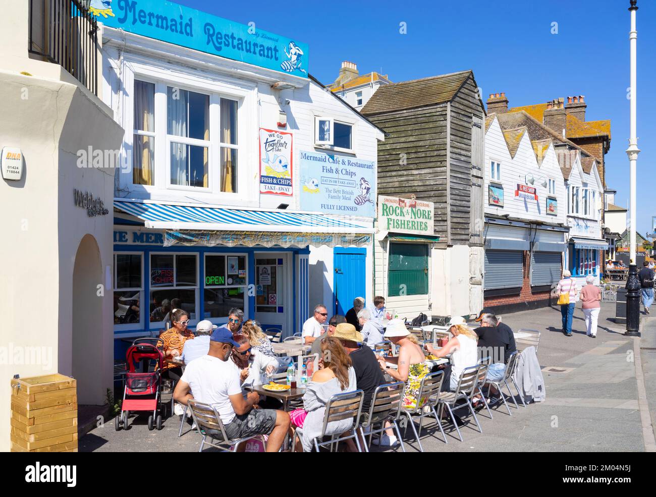 Hastings Old Town People eating fish and chips outside the Mermaid restaurant Hastings old Town Hastings East Sussex England UK GB Europe Stock Photo