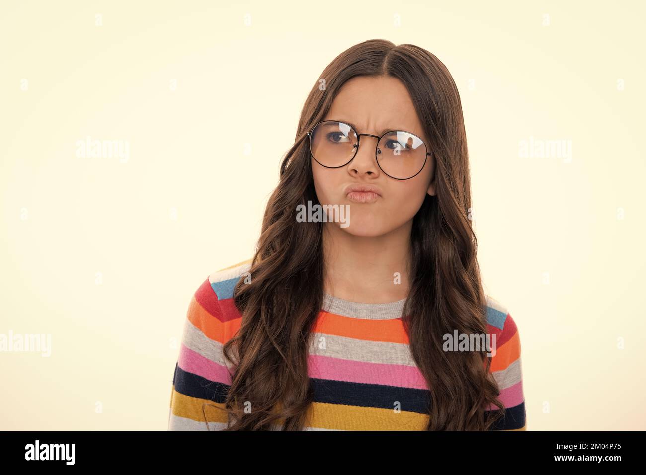 Childhood emotion anger and hate. Teenager girl frowning upset because of problem. Mad young girl isolated in studio background. Furious child. Stock Photo
