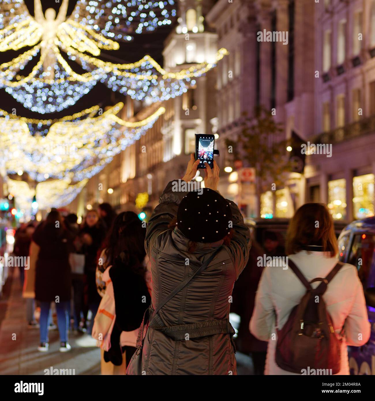 Tourist photographs The Spirit of Christmas Light display on Regent Street with a smart phone. Stock Photo