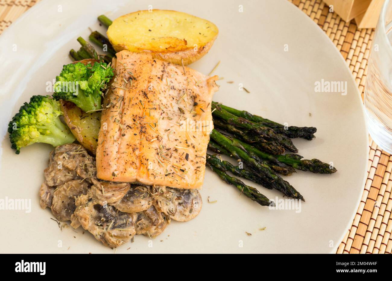 dish of fried river trout fillet with garnish of broccoli, asparagus sprouts and mushroom sauce Stock Photo