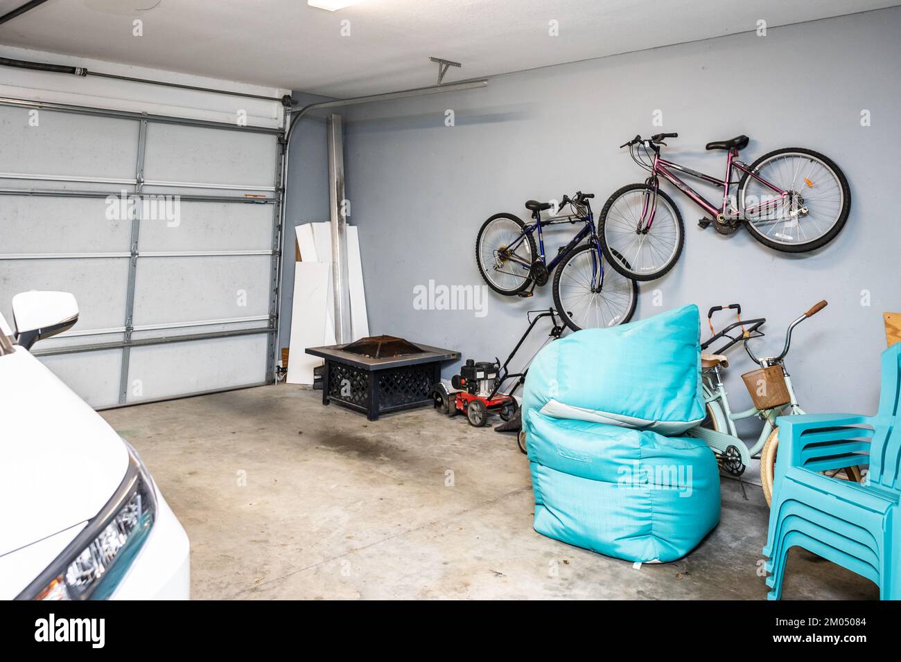 A two car garage that is mostly empty with a car and bicycles organized
