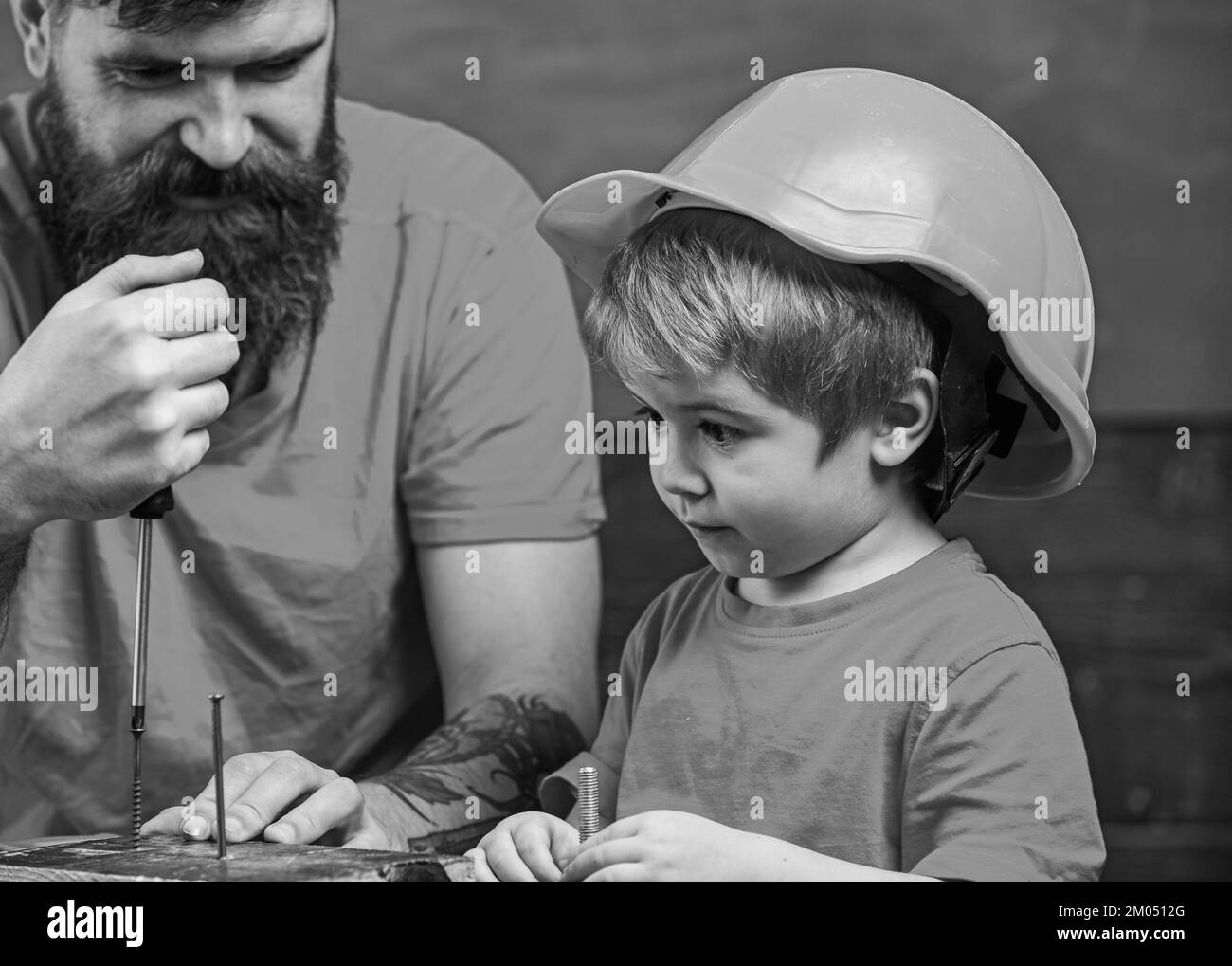 Boy, child busy in protective helmet learning to use screwdriver with