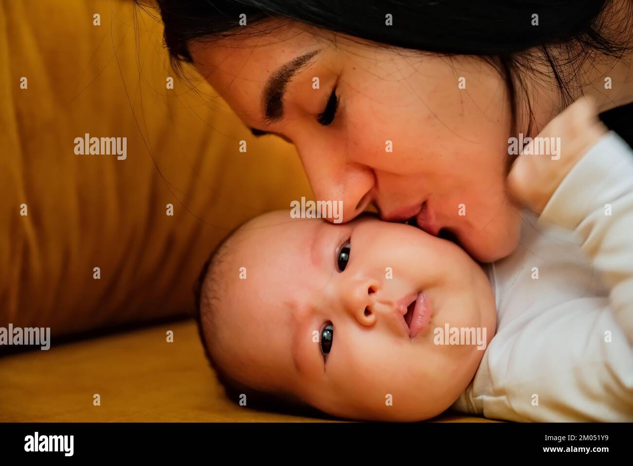 mother kisses the cheek of a newborn. the concept of a kiss, motherly love. Stock Photo