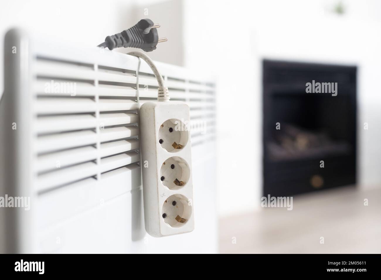 Electric heater plug inserted into extension cord. White radiator for