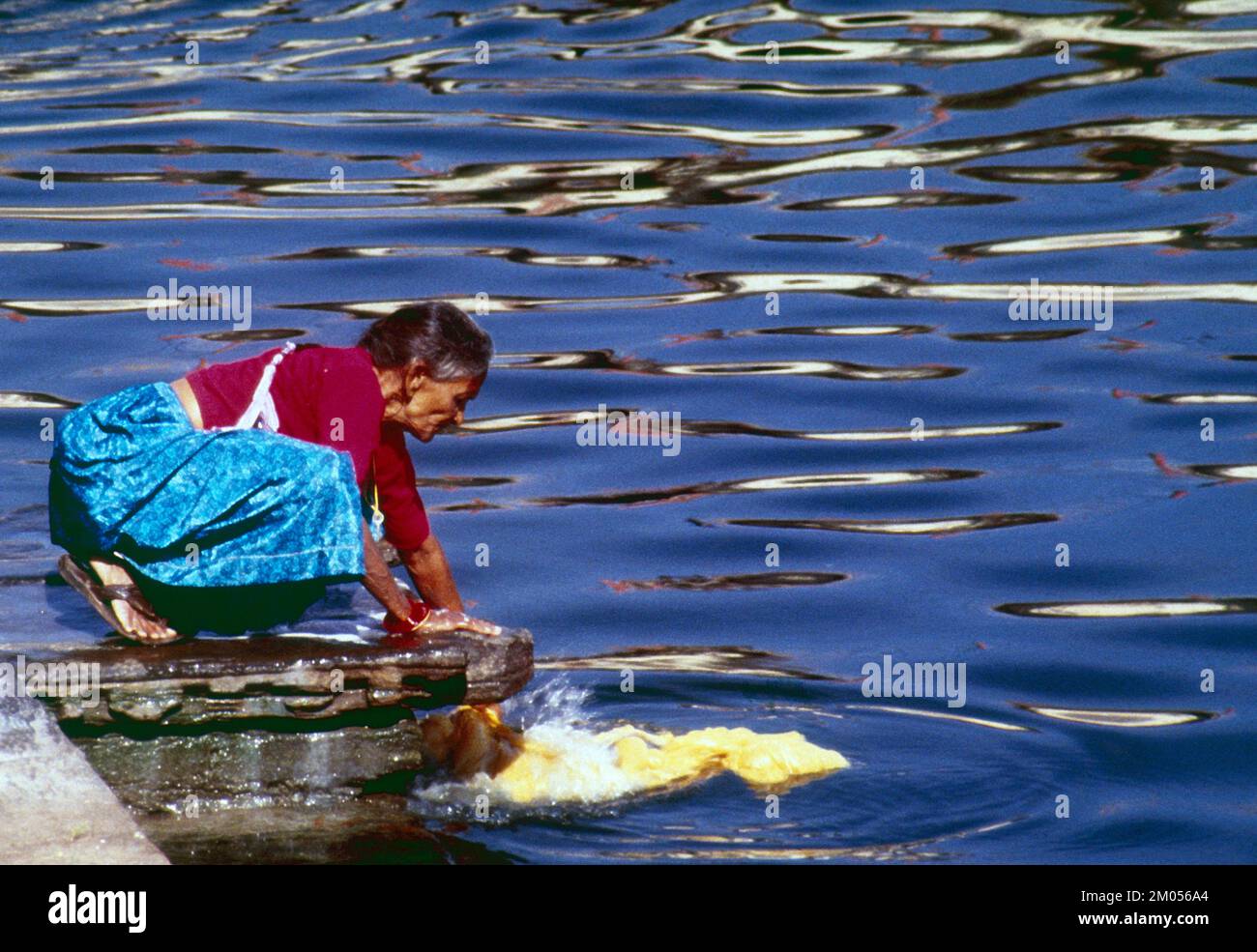 India. Delhi. Old woman washing clothes in the Ganges River. Stock Photo