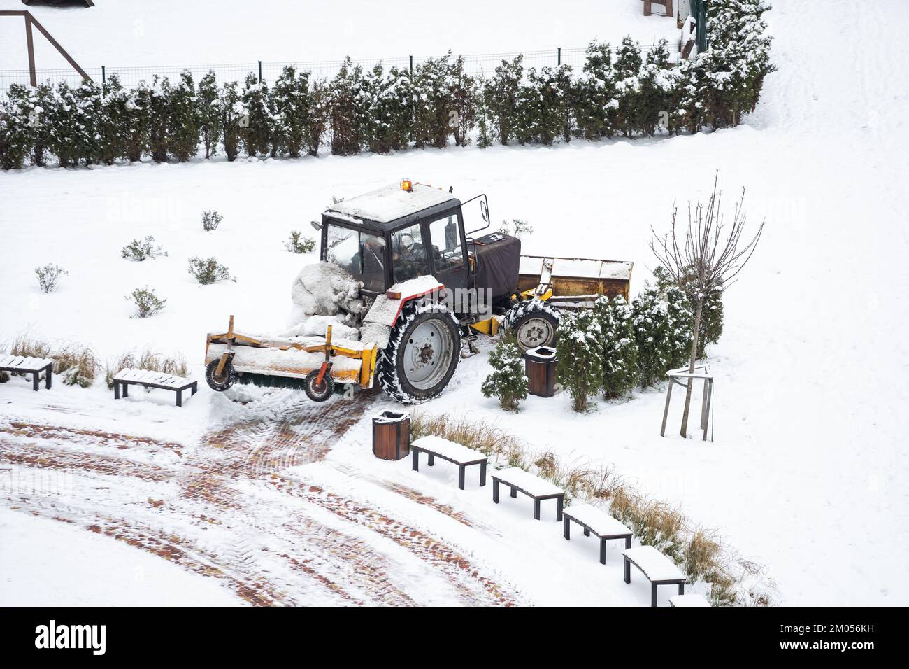 Tractor sweep snow with rotating brush and snowplow from pedestrian