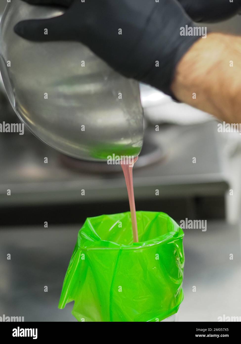 pastry chef filling piping bag filling mixed with edible pink paint for