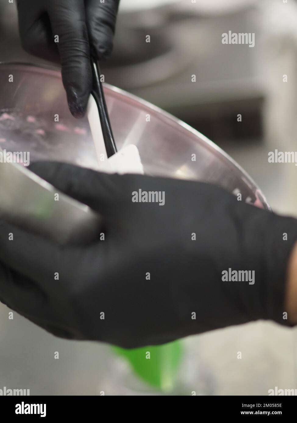 pastry chef stirring piping bag filling mixed with edible pink paint