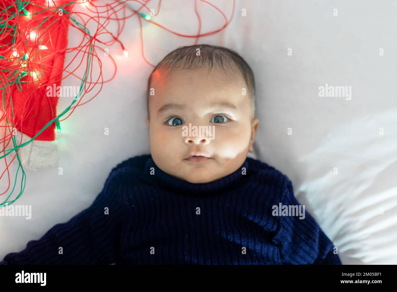 infant boy lying with colorful lights cute facial expression with white background at indoor Stock Photo
