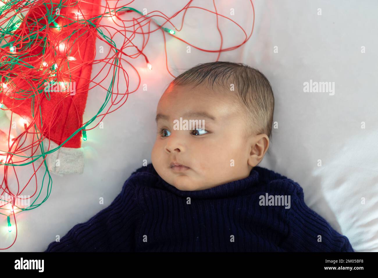 infant boy lying with colorful lights cute facial expression with white background at indoor Stock Photo